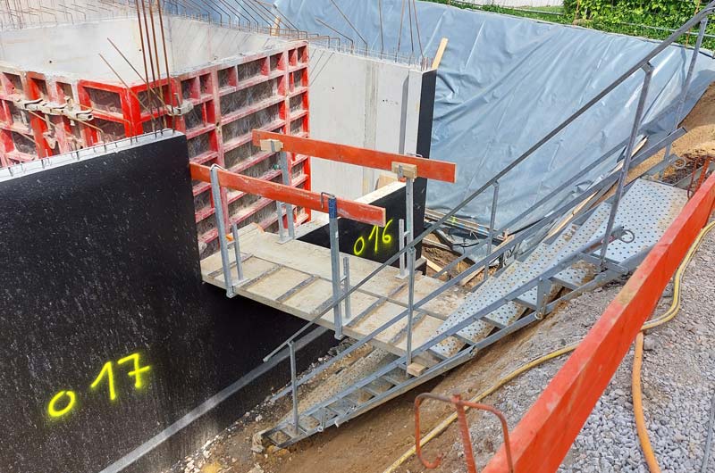 Von einem SiGeKo abgenommene Baustellentreppe mit beidseitigem Handlauf und einem Zugang ebenfalls mit beidseitigem Geländer zur Absturzsicherung.